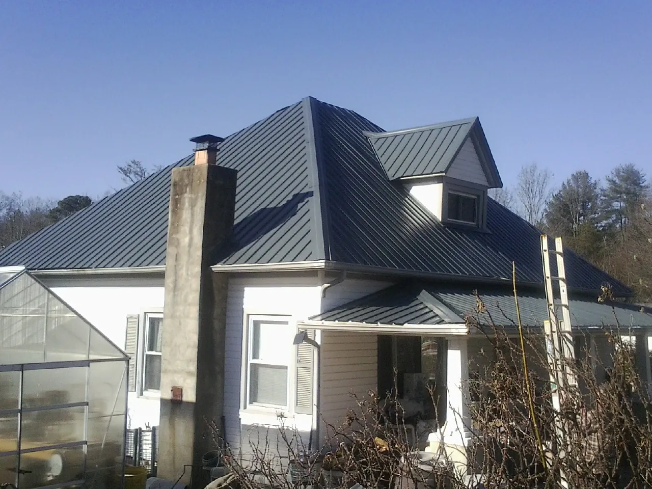 Dark blue standing seam metal roof on a white farmhouse with dormer — Slate & Tile Roof Repair by Roofing Brothers in Blandinsville