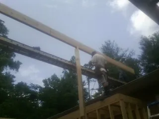 Carpenter setting a ridge beam over a new addition frame — Ice Dam Removal by Roofing Brothers in Blandinsville