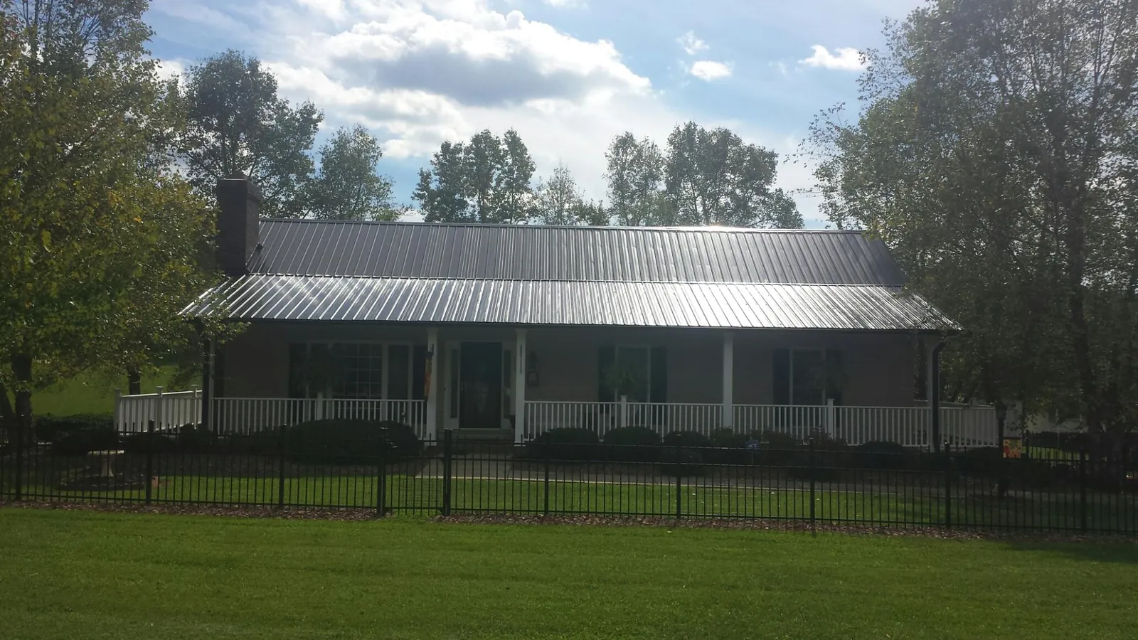 Gray metal roof on a brick ranch with a full width front porch — Gutter Guard Installation work by our crew in Blandinsville