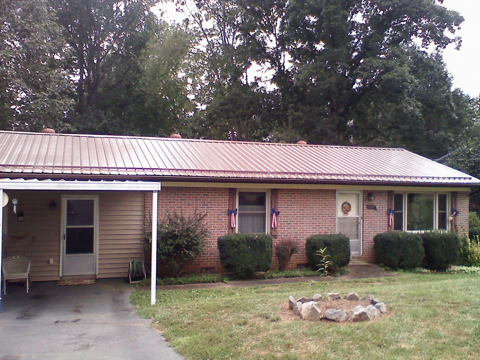 Bronze metal roof and carport on a brick ranch home — Roof Repair work by our crew in Blandinsville