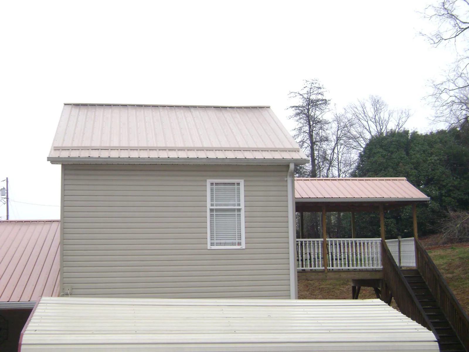 Tan metal roofs on a two story addition and attached porch, from a Roof Replacement job in Blandinsville
