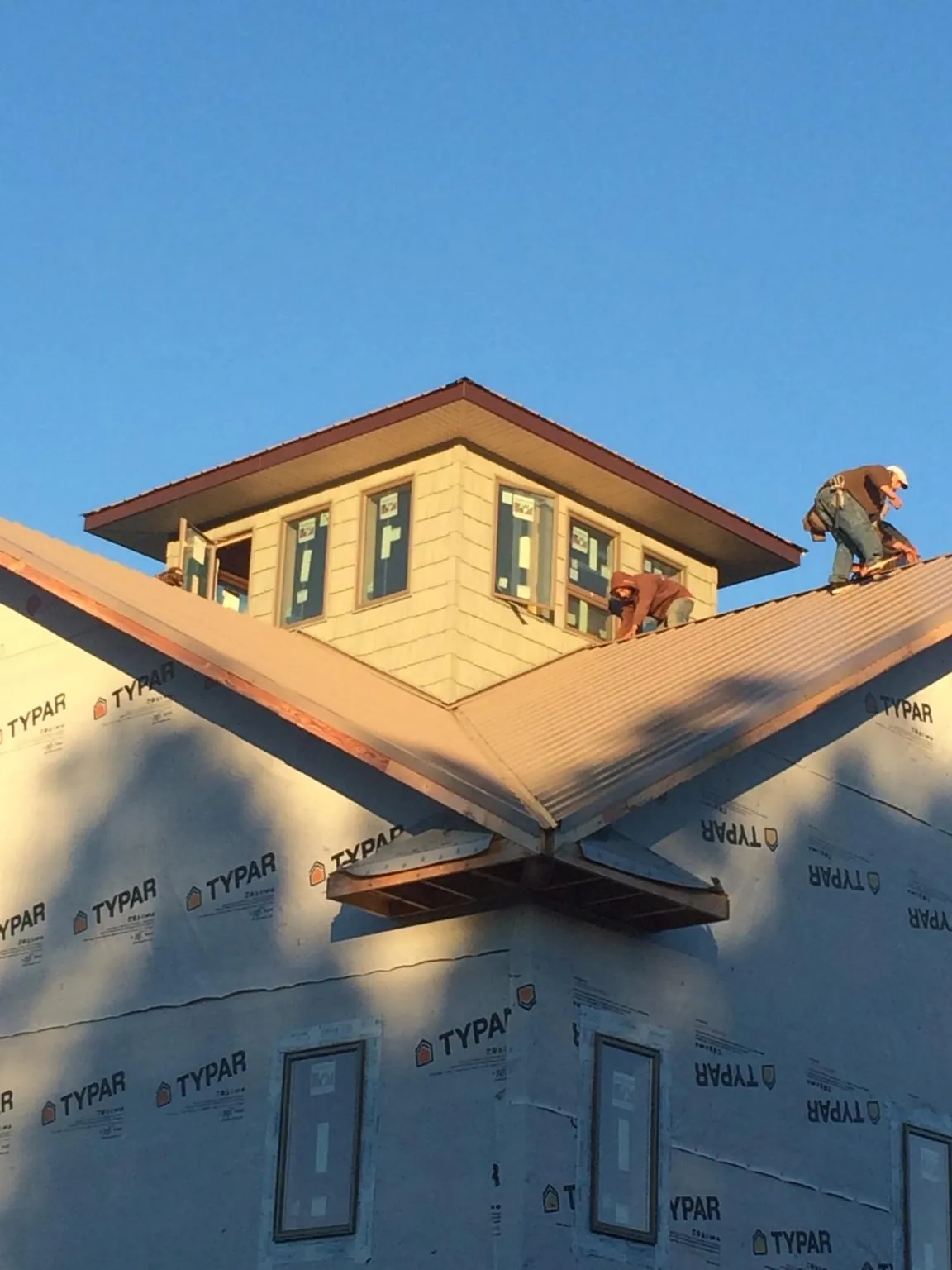 Roofers working around a rooftop cupola on a new metal roof at sunset — Roof Waterproofing in Blandinsville by Roofing Brothers